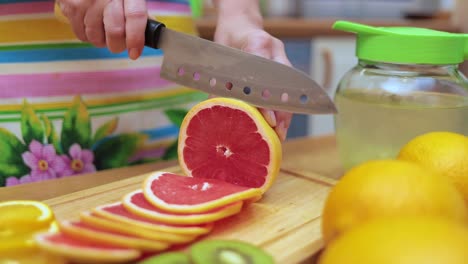 Frauenhände-Hausfrauen-Schneiden-Mit-Einem-Messer-Frische-Grapefruit-Auf-Dem-Schneidebrett-Des-Küchentisches